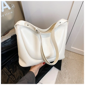 Detail of white PU leather shoulder bag featuring golden logo and side rivet accents
