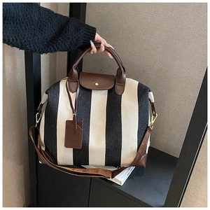 Détail du sac cabas en toile à rayures noires et blanches avec finitions en cuir brun