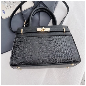 Close-up of black crocodile pattern faux leather handbag with metal twist lock and strap