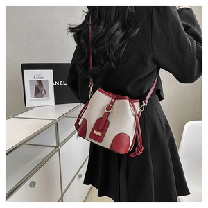 Detail view of cream canvas bucket bag with red leather trim on a fashion model