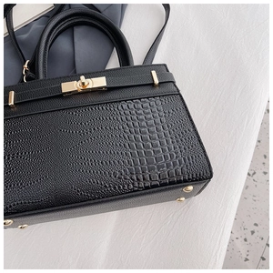 Detailed shot of black litchi and crocodile texture leather with golden twist lock hardware