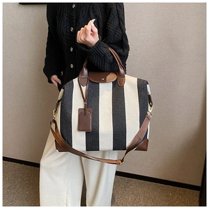 Détail d'un grand sac cabas rayé noir et blanc avec poignées et bandoulière en cuir