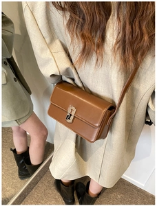 Close-up of vintage brown leather saddle bag with golden H-shaped metal buckle detail