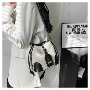 Detail of the canvas bucket bag with black leather trim and gold hardware accents