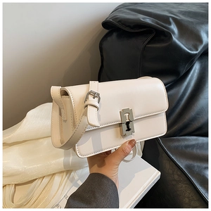 Detail of a creamy white saddle bag featuring a unique silver razor blade metal buckle