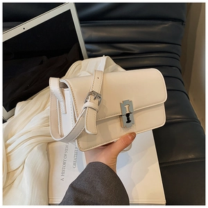 Detail of cream saddle bag featuring a unique silver blade-shaped metal buckle closure