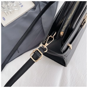 Close-up of black lychee texture leather with premium gold metal hardware and adjustable strap