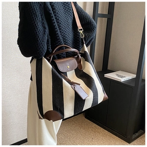 Détail du cabas en toile à rayures noires et blanches avec poignées en cuir marron