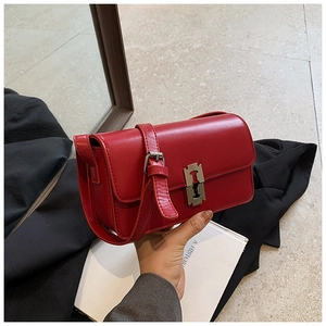 Detail of red faux leather shoulder bag featuring a silver H-shaped metal buckle lock