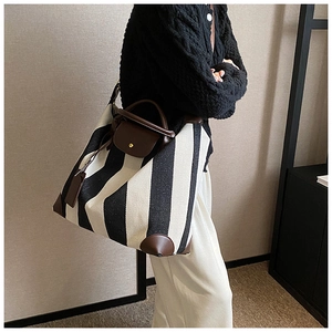 Détail du sac cabas en toile rayée noir et blanc avec garniture en cuir marron et sangle