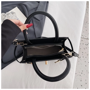 Top view of black lychee leather handbag featuring interior zipper pocket and gold hardware