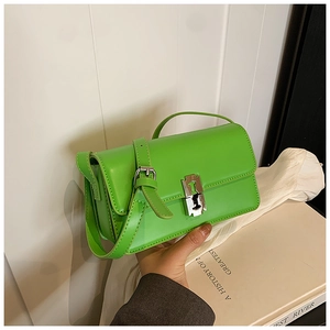 Detail of a lime green patent leather saddle bag with a silver razor-blade metal clasp