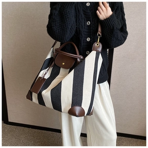 Détail du sac cabas en toile rayée avec poignées en cuir marron et bandoulière réglable