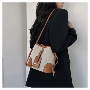 Side view of contrast bucket bag in canvas and leather on a model in black blazer