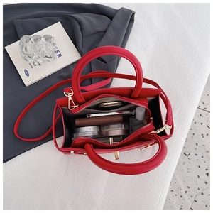 Top view of red lychee pattern handbag interior holding phone, wallet and cosmetics