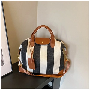 Détail du sac cabas en toile rayée avec poignées en cuir marron et bandoulière réglable