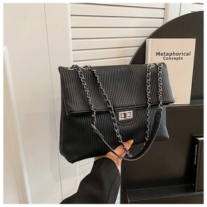 Detail of black vertical pleated crossbody bag with silver metal turn-lock and chain strap