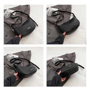 Detail view of the black pleated crescent bag with its distinctive gold brand plaque