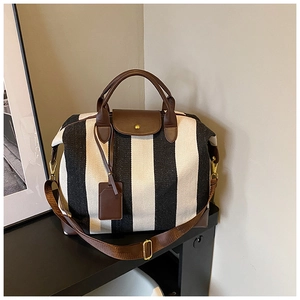 Détail du grand sac de voyage à rayures avec poignées en similicuir brun et étiquette