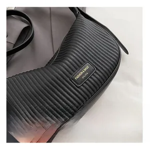 Detail of black quilted leather hobo bag with a gold-stamped brand logo and pleated texture