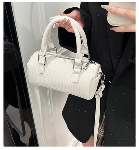 Detailed view of white faux leather barrel bag with vertical texture and silver hardware