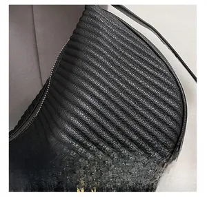 Close-up of black pleated dumpling bag showing premium quilted leather and gold lettering
