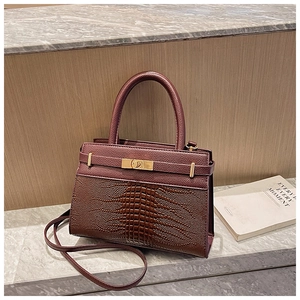 Detail of burgundy textured bag showing faux crocodile pattern and golden metal turn-lock