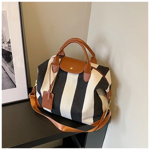 Détail d'un sac de voyage en toile rayée avec poignées en cuir marron et rabat