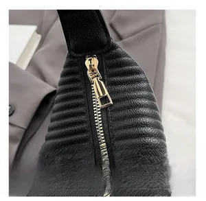 Detailed close-up of smooth gold metal zipper on black pleated faux leather bag