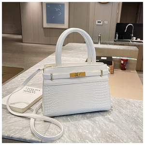 Detail of white crocodile embossed texture handbag with golden lock and top handle