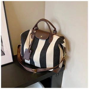 Détail du sac cabas en toile à rayures noires et blanches avec finitions en cuir brun