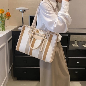 Large striped canvas tote bag with beige leather handles for women in a stylish room