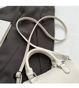 Detail of white pleated leather texture and silver hardware on a crossbody handbag