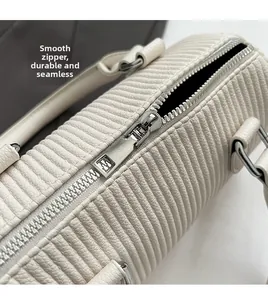Detail of smooth metal zipper and textured pleated fabric on cream handbag