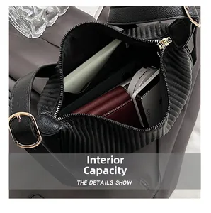 Internal capacity of black pleated shoulder bag showing phone, wallet, and cosmetics
