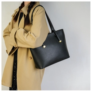Détail du cabas en cuir grainé noir avec boucles métalliques dorées sur la bandoulière