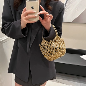 Detail view of a hollow-out gold metal woven evening bag with elegant chain handle