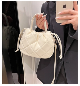 Detail of a creamy white quilted PU leather cloud bag with drawstring and shoulder strap