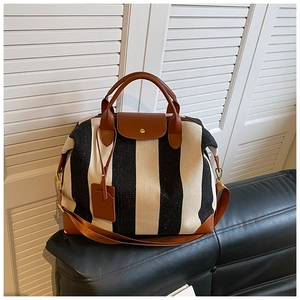 Détail d'un sac de voyage rayé avec garniture en cuir marron et finitions dorées