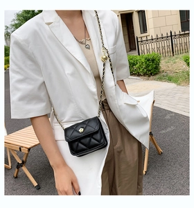 Detail of mini quilted crossbody bag featuring a golden camellia clasp and chain strap