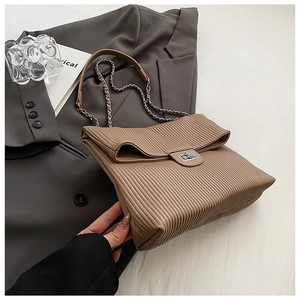 Close-up of brown pleated PU leather texture with silver metal twist lock and chain strap
