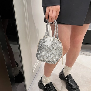 Close-up of a silver woven metal bucket bag with white drawstring lining and metallic handles