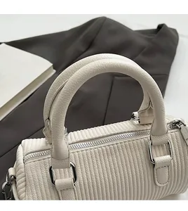 Detail of white cylinder bag showing textured faux leather and silver metal handles
