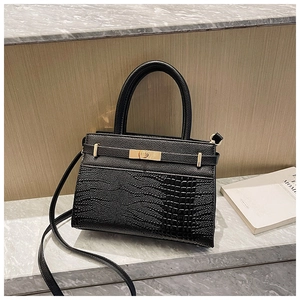 Detail of black crossbody bag with mixed pebble and crocodile textures on marble surface
