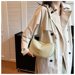 Detail of light green pleated croissant bag featuring fine texture and leather logo tag