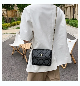 Close-up of quilted chain bag with gold floral buckle on a female model in outdoor setting
