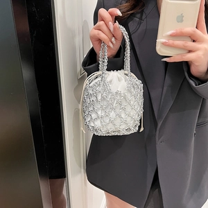 Detail of silver woven chain bucket bag with a white satin drawstring lining inside