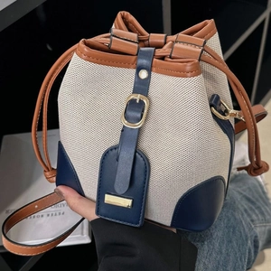Contrast canvas and leather bucket bag with drawstring closure and golden metal buckle