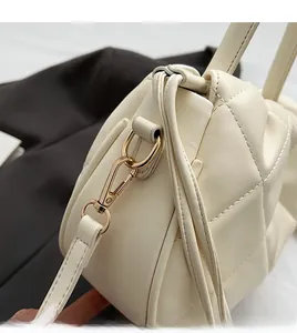 Detailed close-up of durable golden metal hooks and white quilted leather strap on a bucket bag