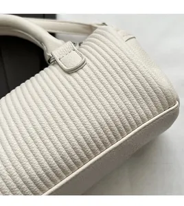 Close-up of white pleated pillow bag texture with soft grain faux leather and metal rings